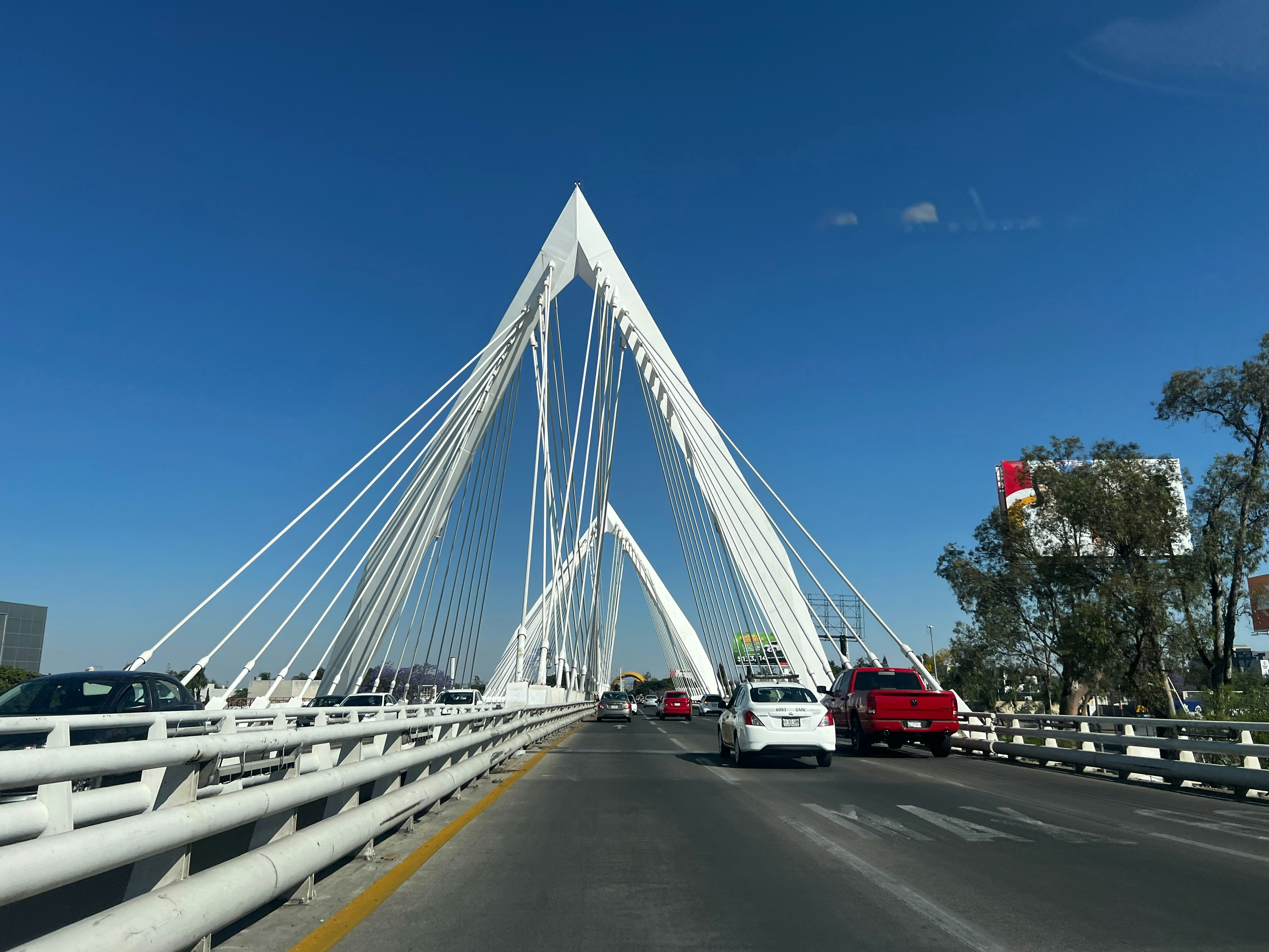 cars driving on a bridge with a blue sky in the background