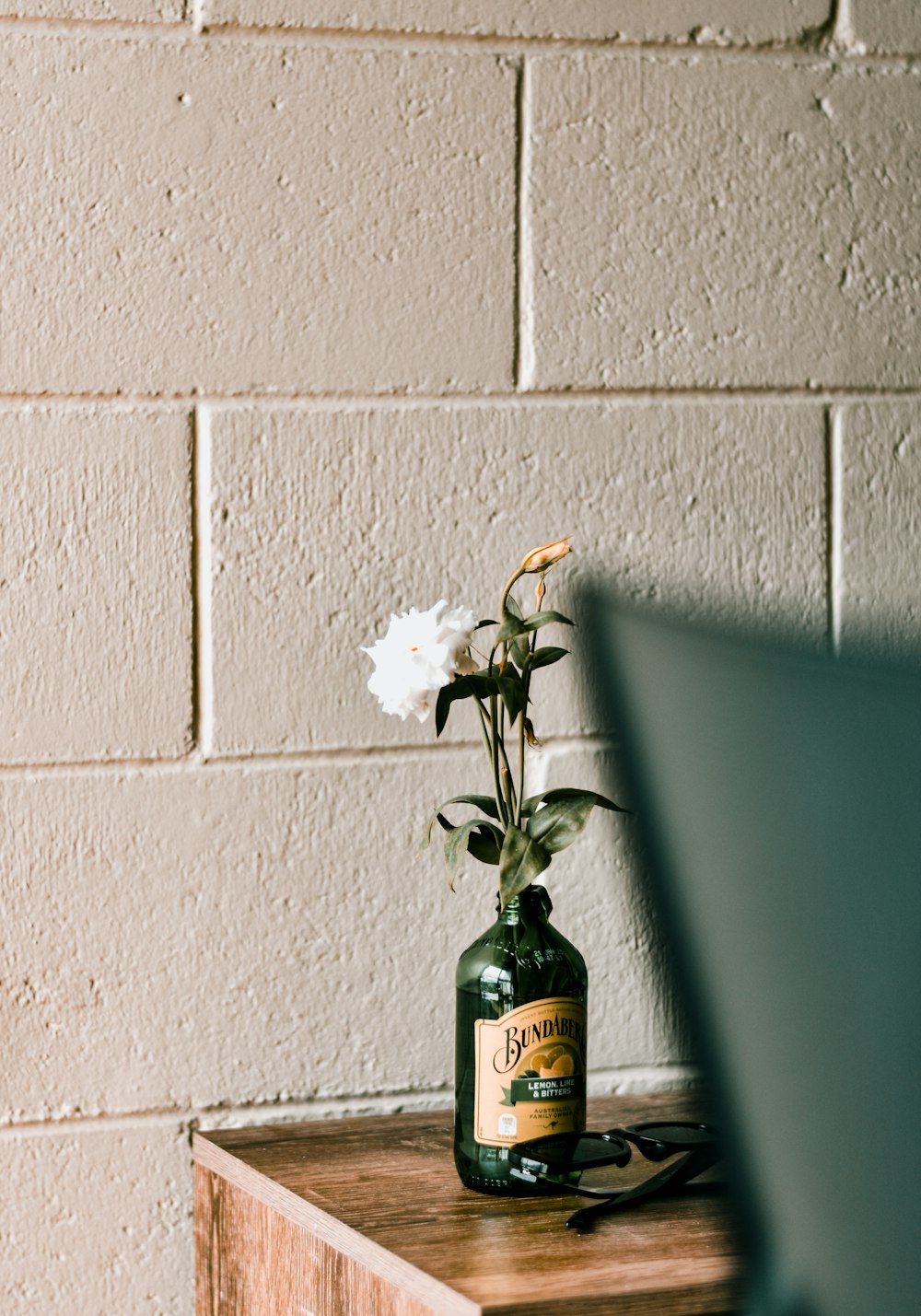 a bottle with a flower in it sitting on a table