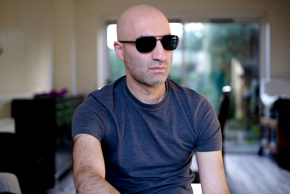a bald man wearing sunglasses sitting in a chair
