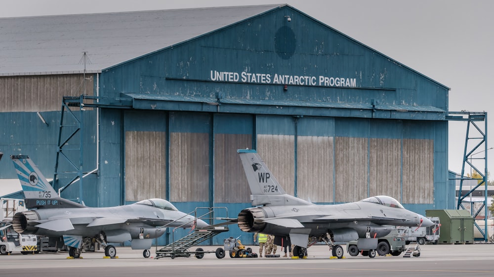 a couple of fighter jets parked in front of a building