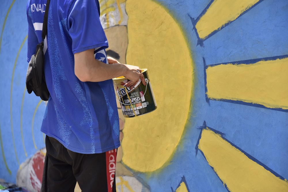 a person standing in front of a wall with a painting on it