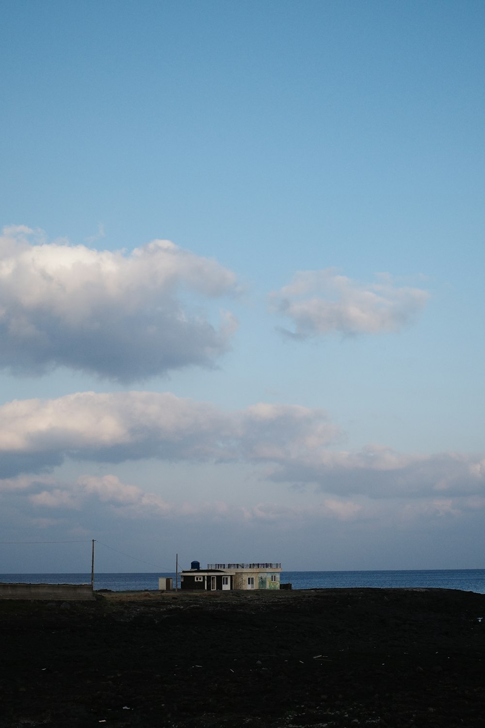 a small building sitting on top of a field next to the ocean