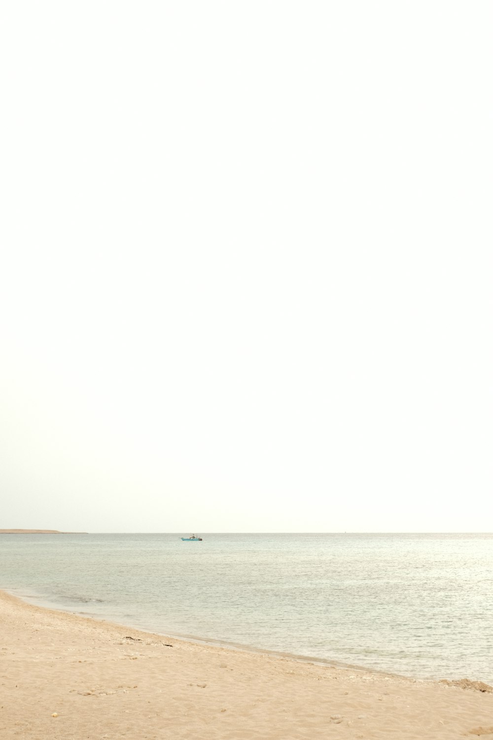 eine Person, die mit einem Surfbrett am Strand spazieren geht