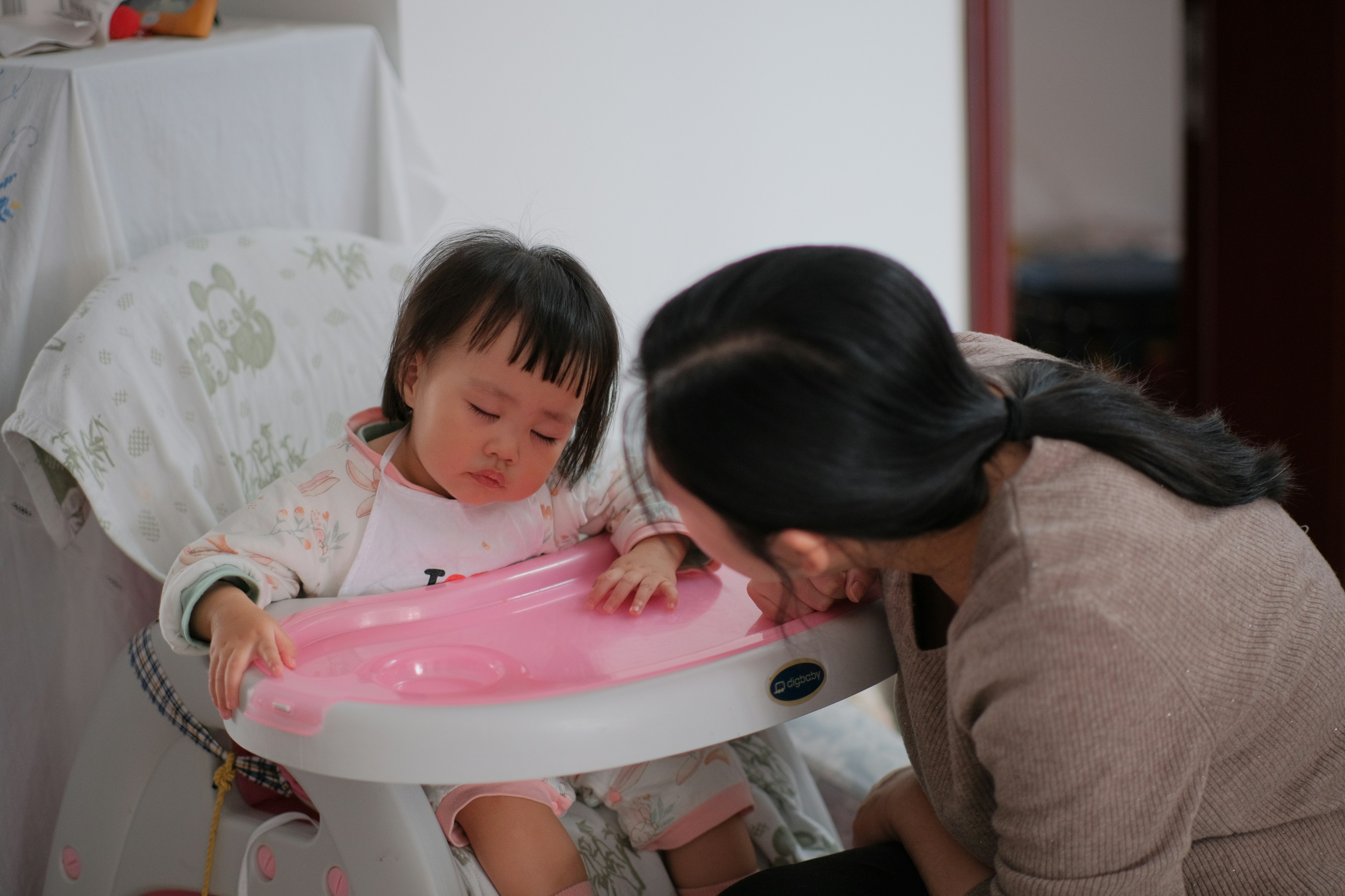 Parent cleaning a baby high chair with a non-toxic spray - earth friendly baby cleaner