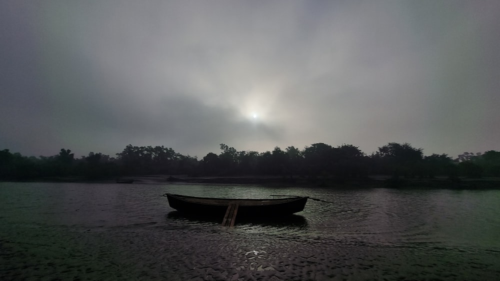 a boat floating on top of a lake under a cloudy sky