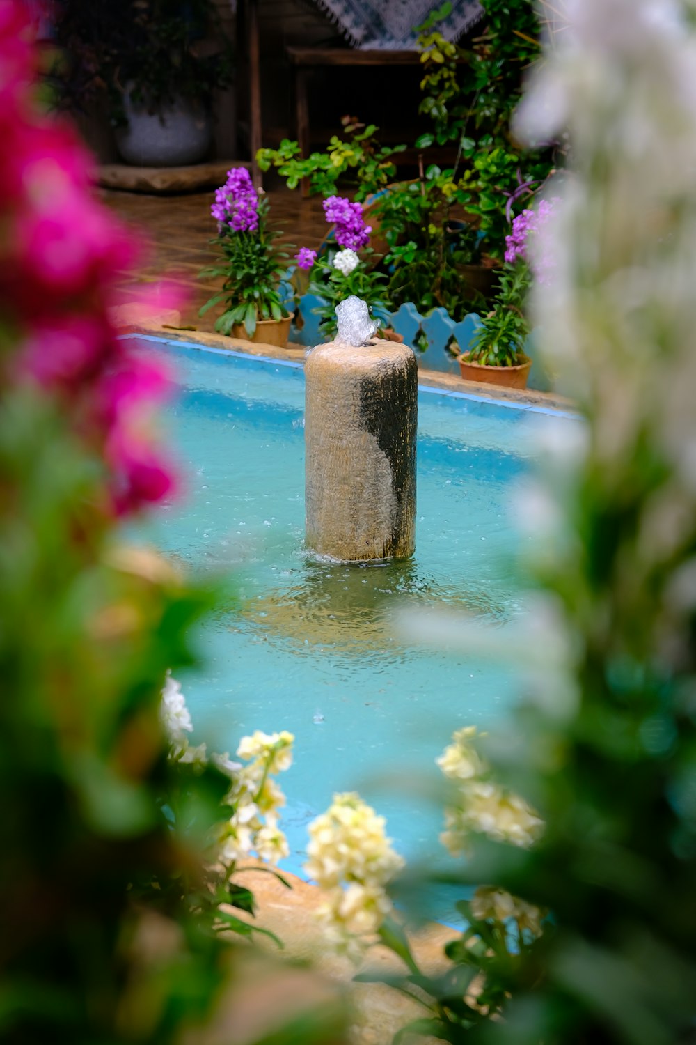 a water fountain surrounded by flowers in a garden