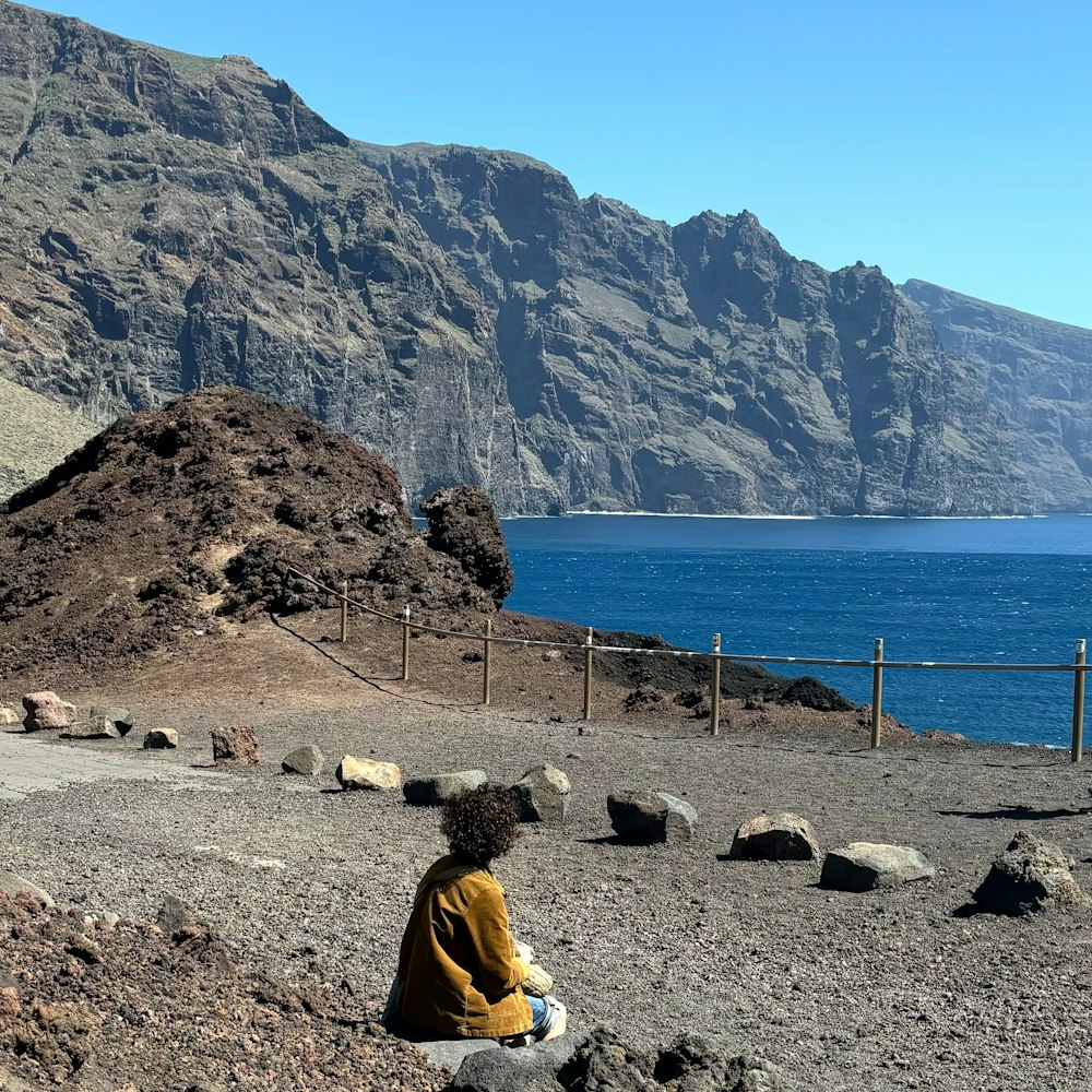 a person sitting on a rock near a body of water