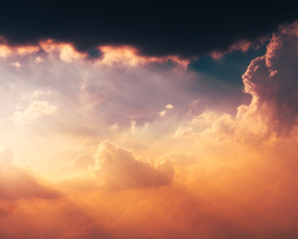 a plane flying through a cloudy sky at sunset