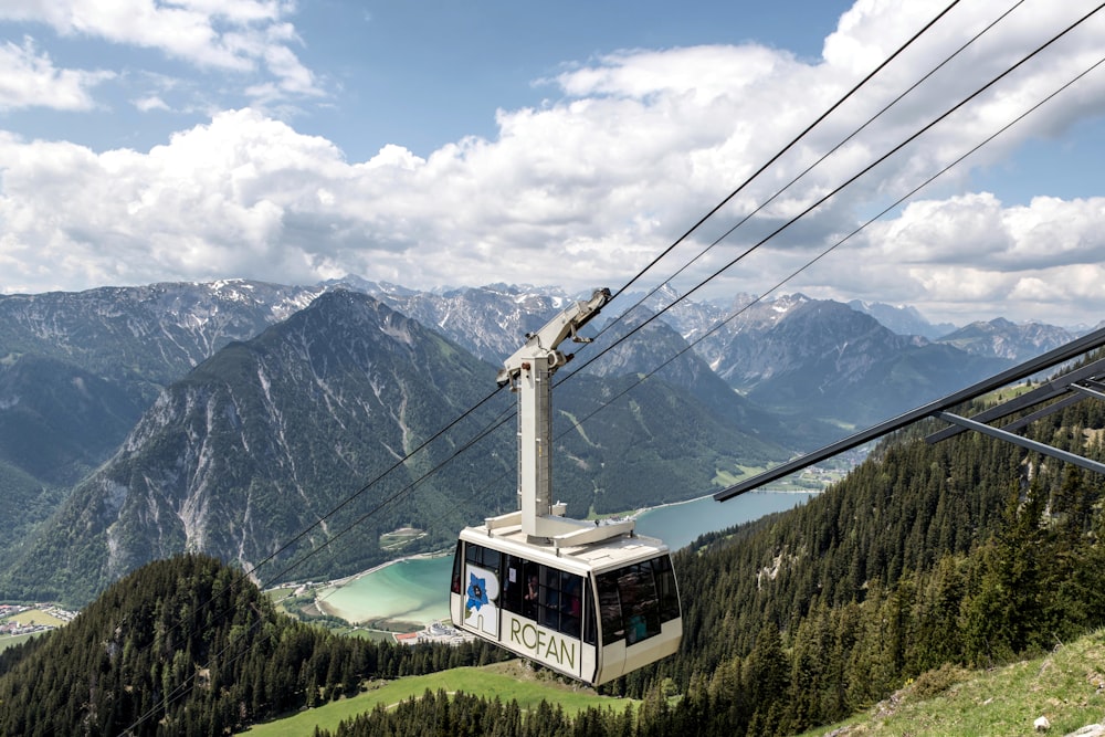 a cable car going up a mountain with a lake in the background