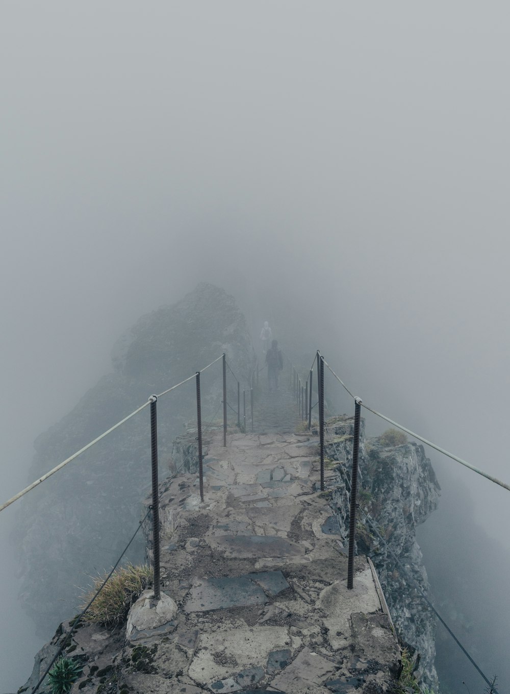 a man walking across a bridge on a foggy day