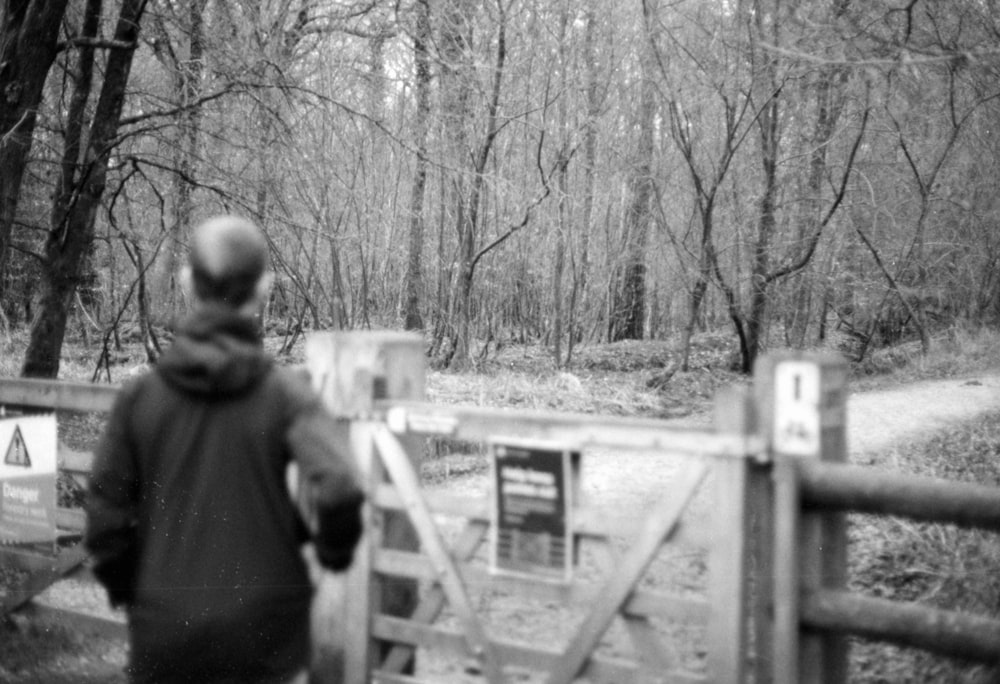 a black and white photo of a person walking over a bridge