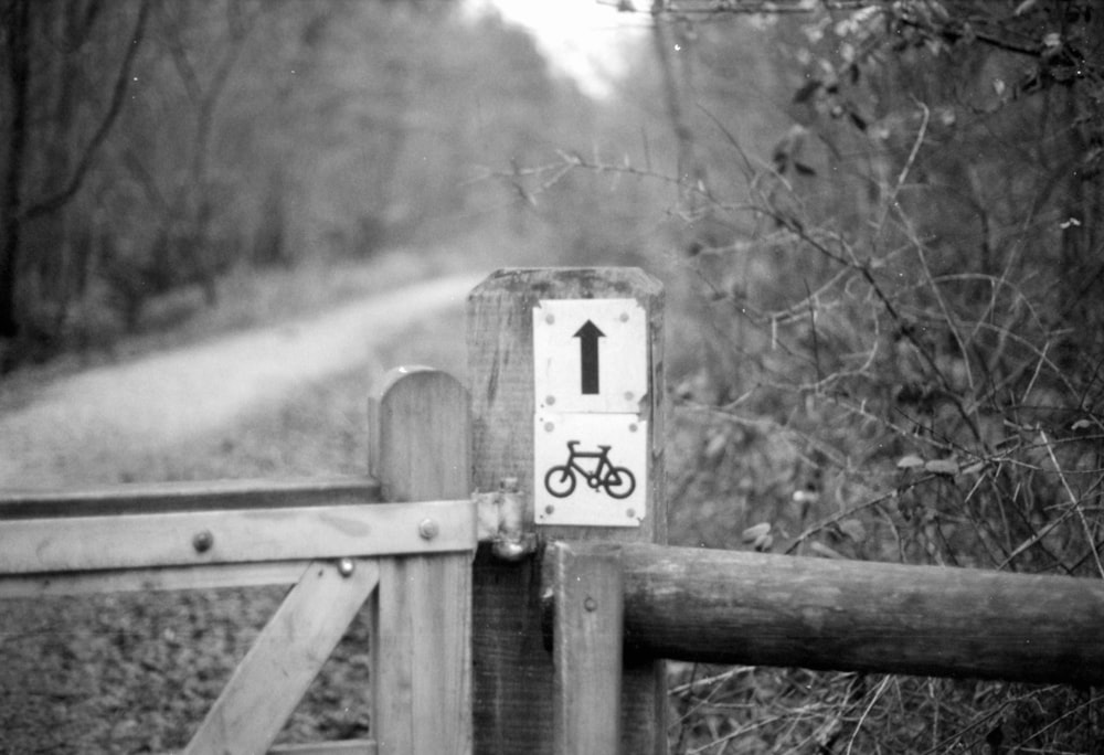 un cartello di bicicletta su un cancello di legno nel bosco