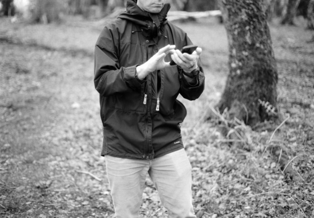 a man standing in the woods looking at his cell phone