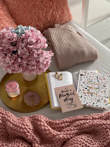 a bed with a pink blanket and a vase of flowers