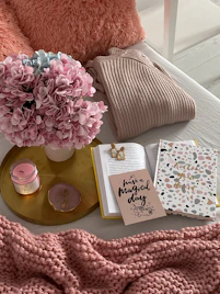 a bed with a pink blanket and a vase of flowers