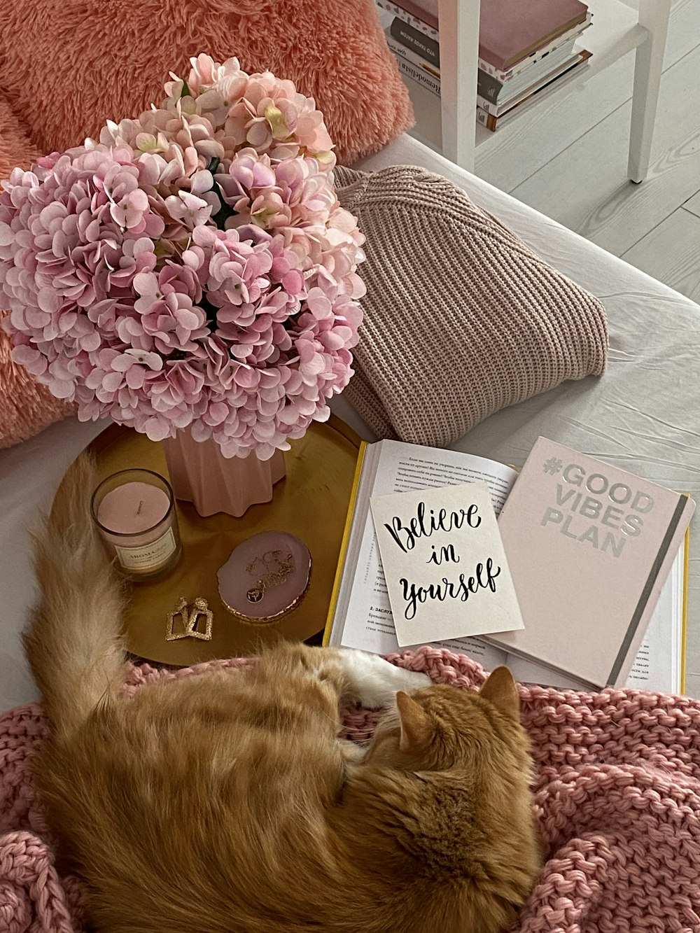 a cat laying on a blanket next to a vase of flowers