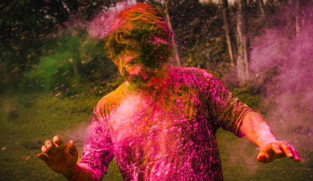 um homem coberto de pó colorido jogando pó colorido