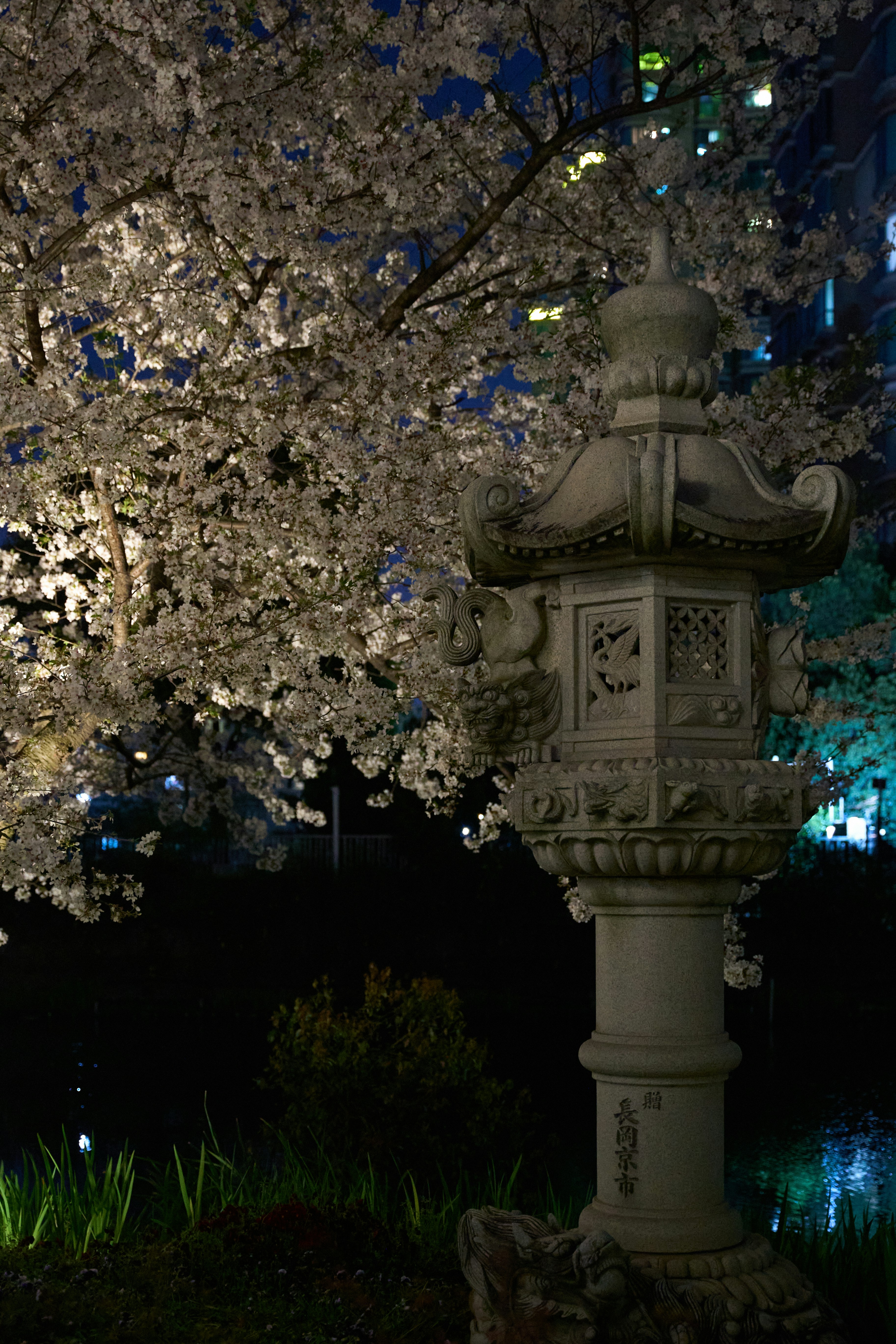 a tall white clock sitting next to a tree