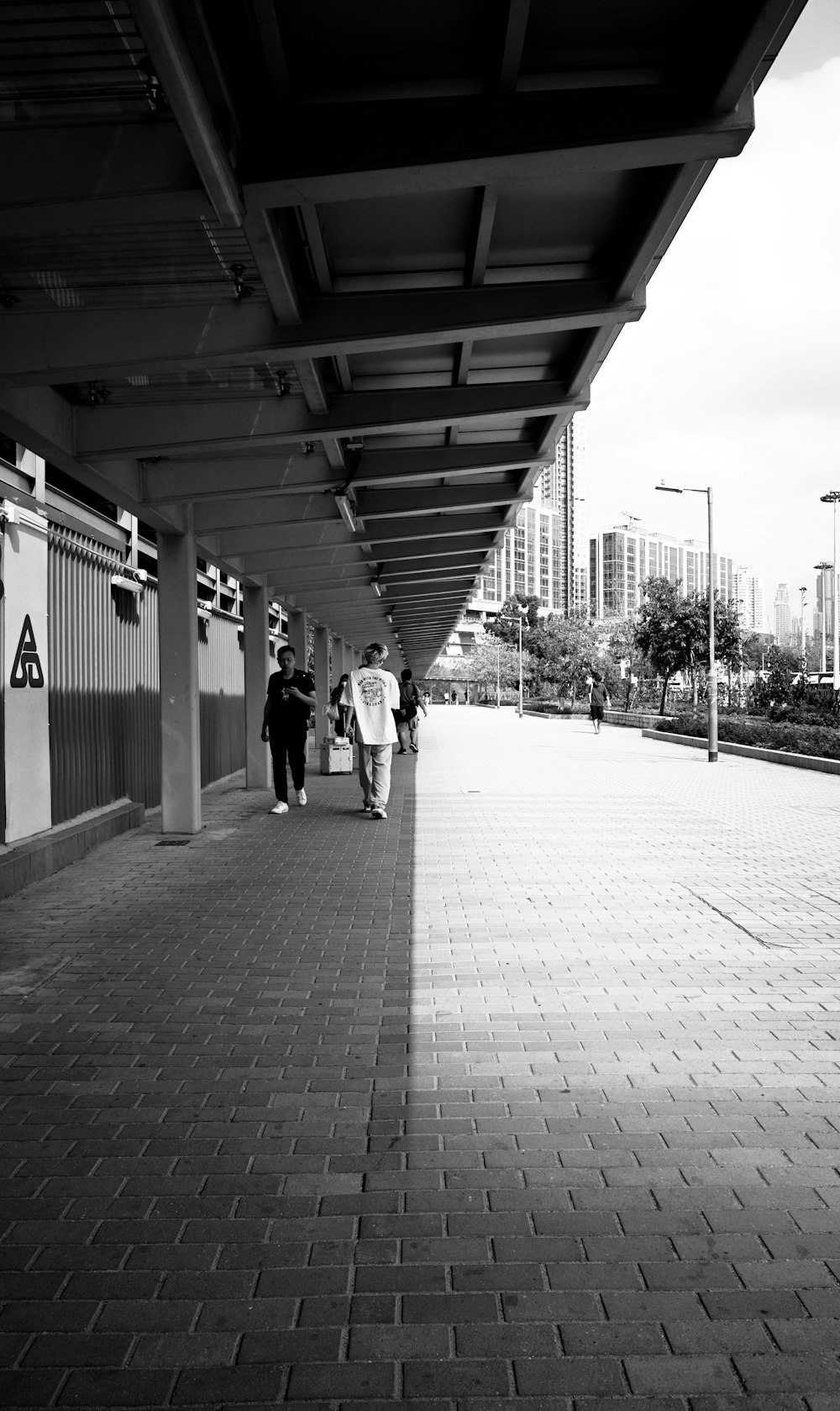 a black and white photo of people walking down a sidewalk