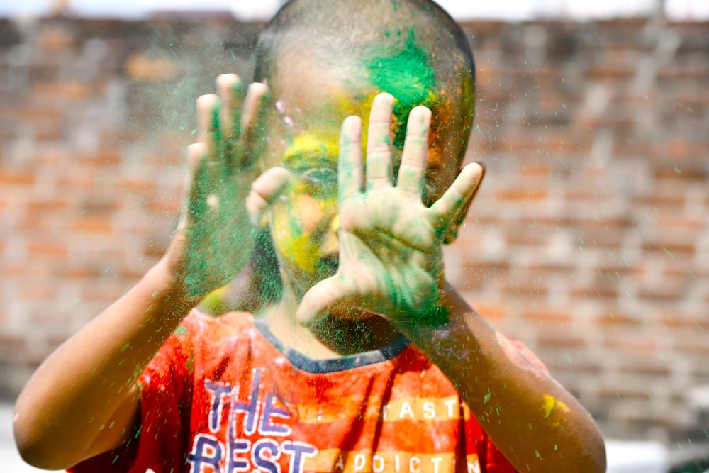 a young boy is covered in colored powder