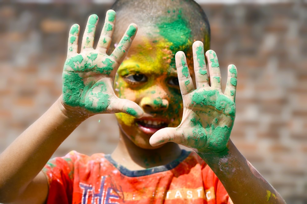 a young boy is covered in green and yellow paint