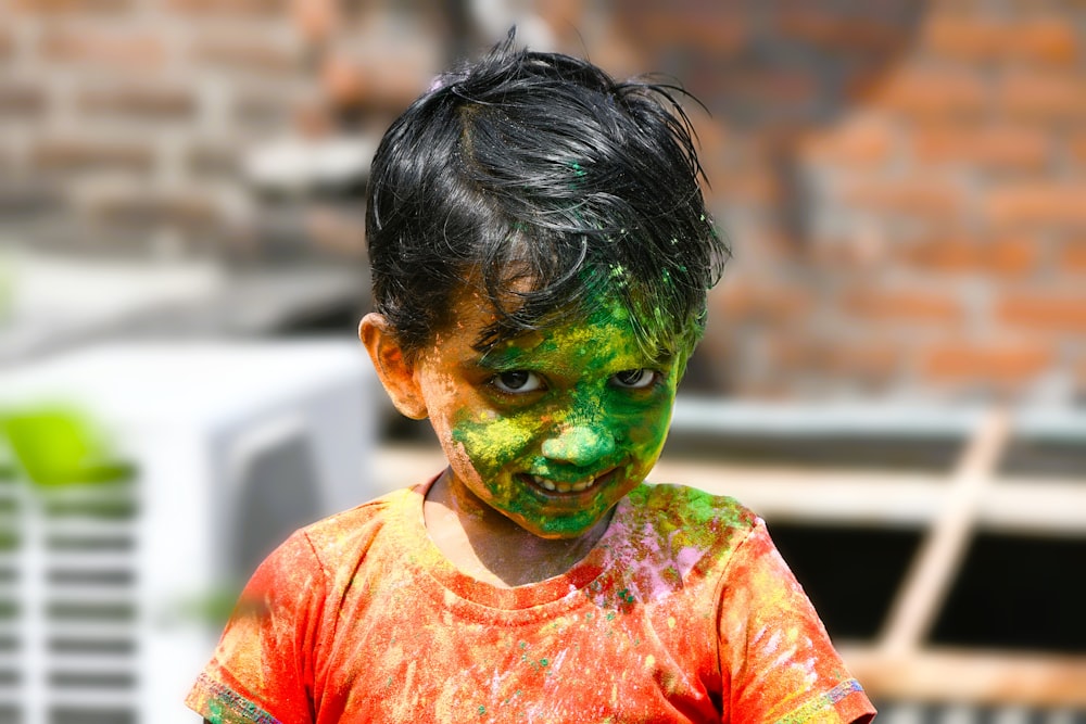 a young boy with green and orange paint on his face