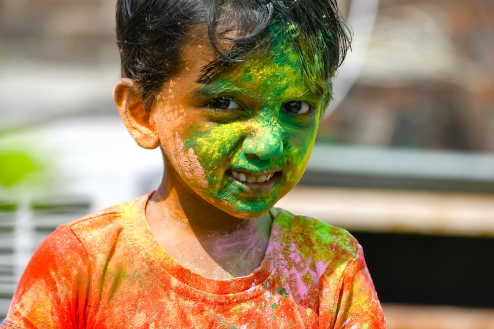 a young boy covered in green and orange paint