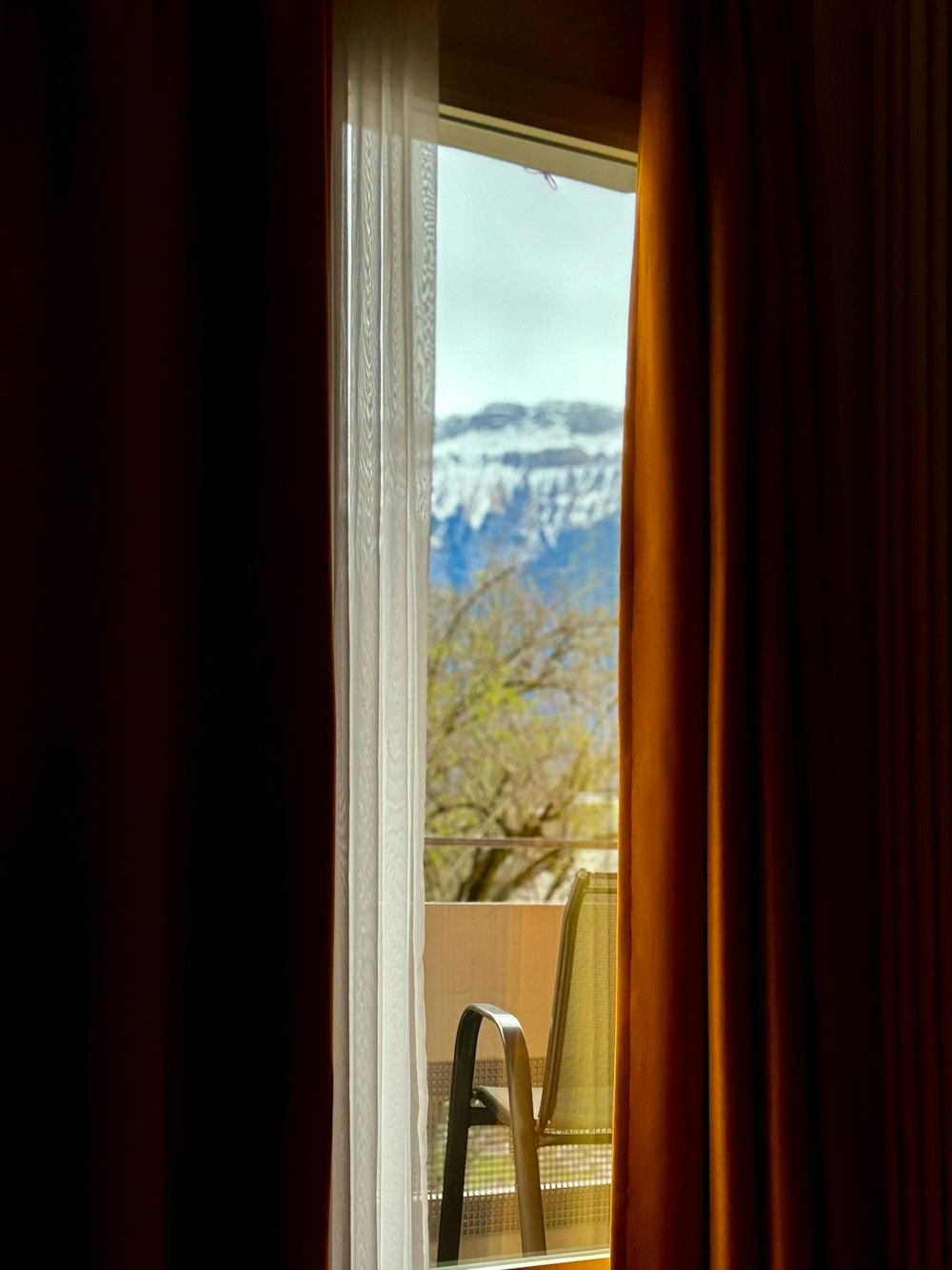 a chair sitting in front of a window with a mountain view