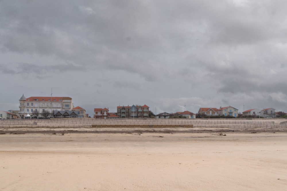 a sandy beach with houses in the distance