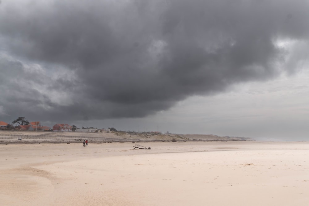 a cloudy day at the beach with people walking on the sand