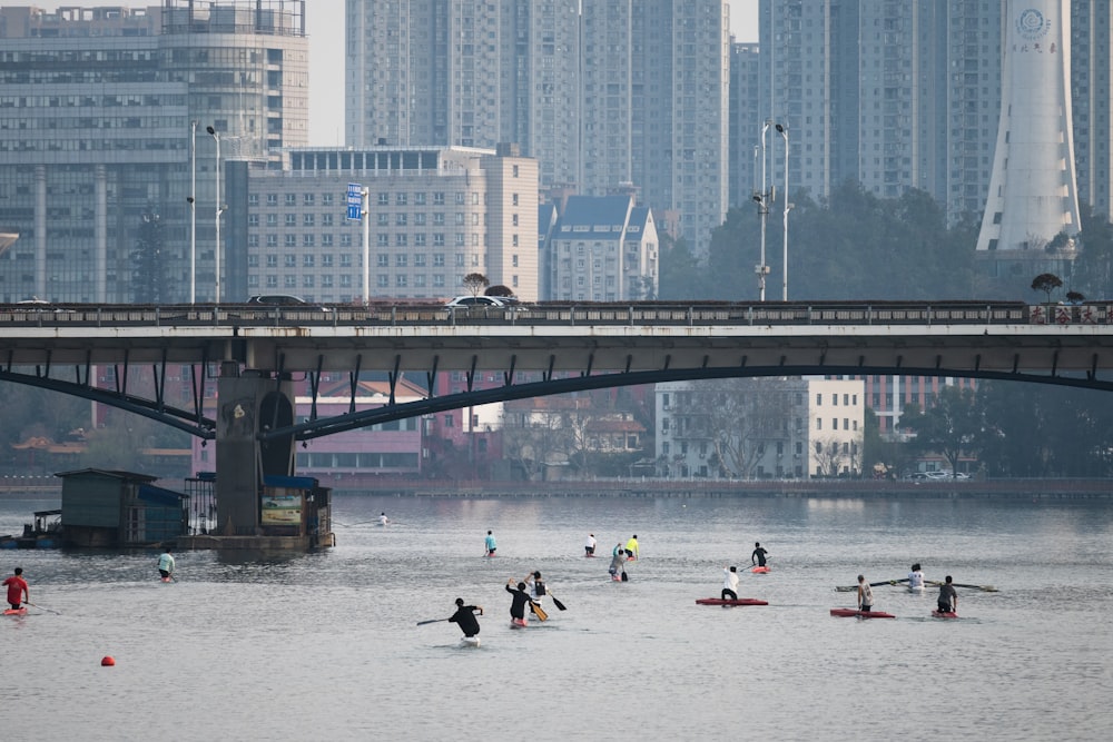 um grupo de pessoas parado na água perto de uma ponte