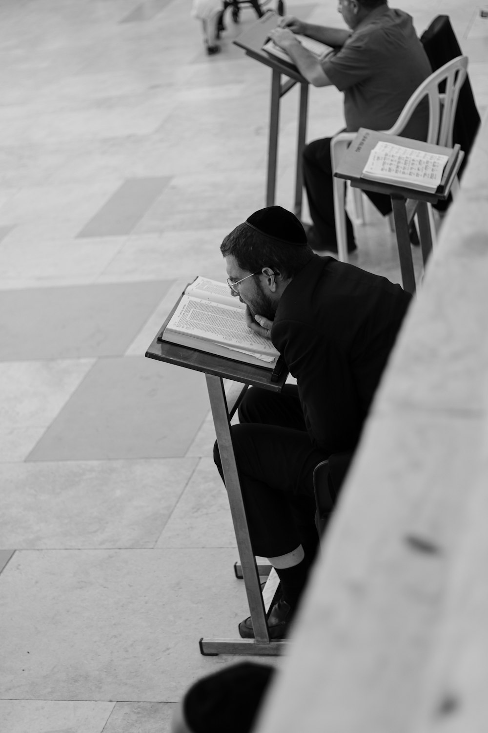 um homem sentado a uma mesa com um livro no colo