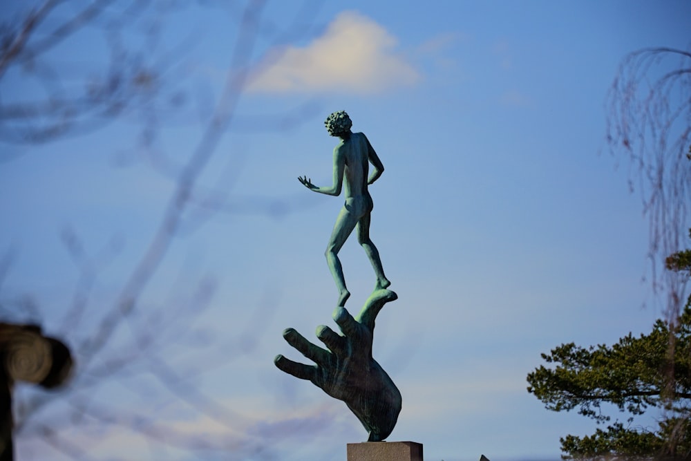 a statue of a man standing on top of a hand
