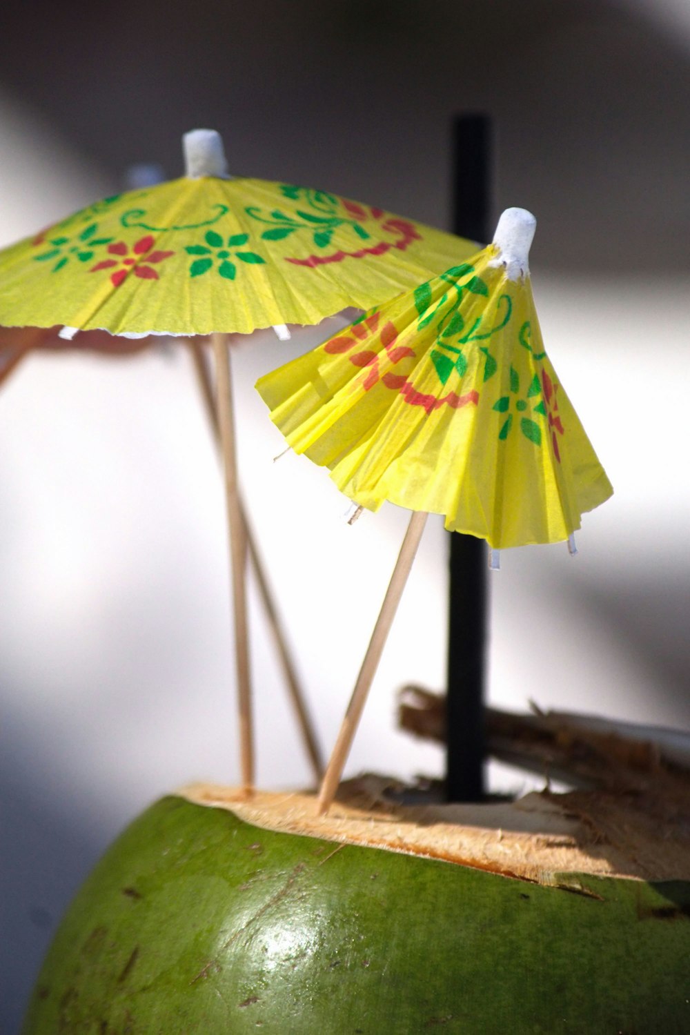 une noix de coco verte avec un parapluie jaune sur le dessus