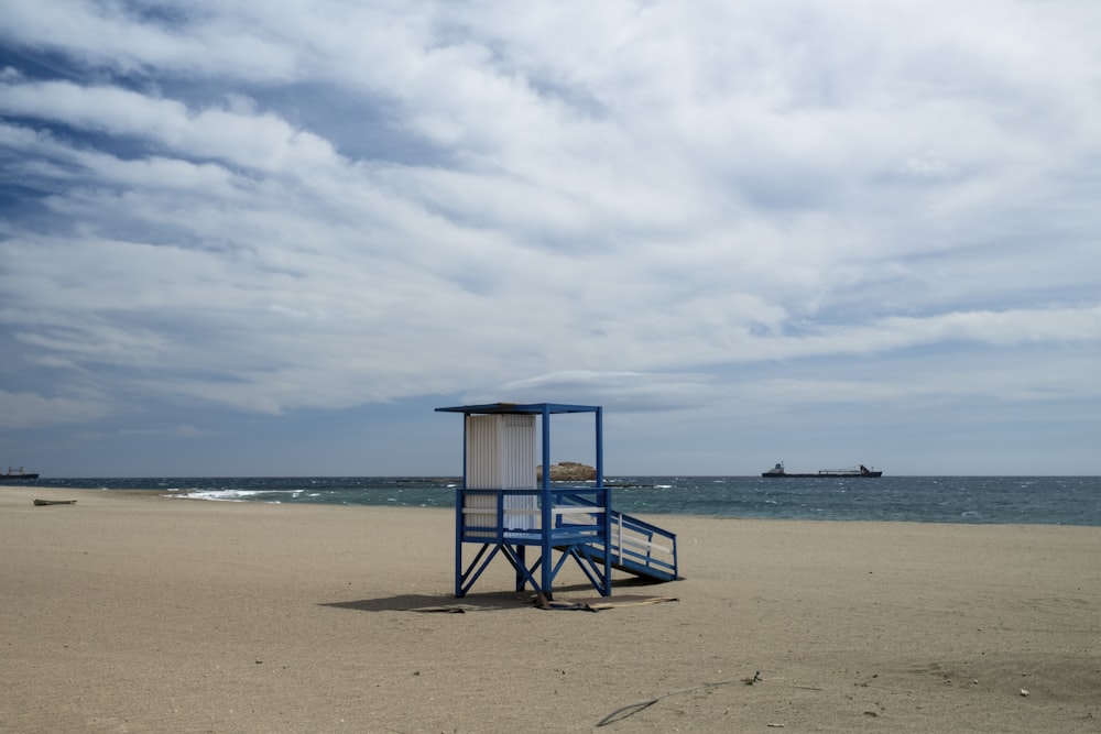 a lifeguard stand on a beach with a boat in the background