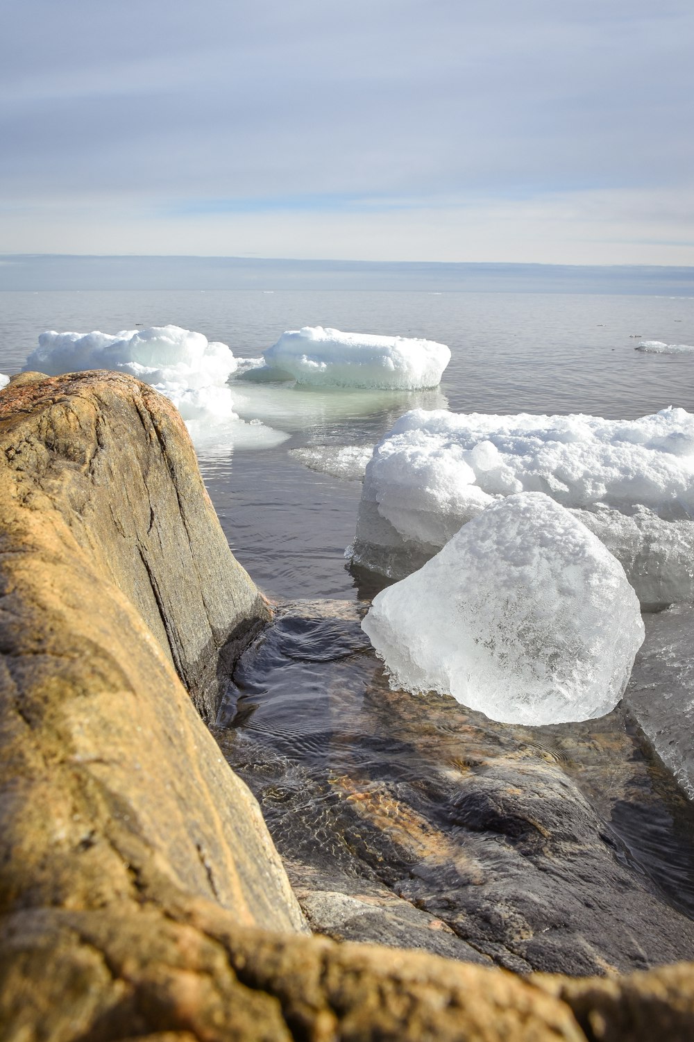 icebergs floating in a body of water near rocks