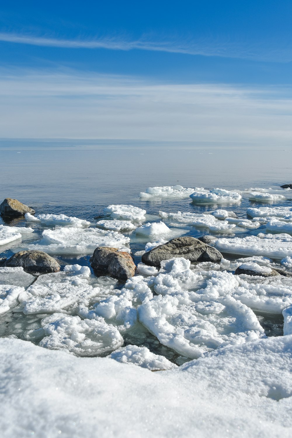 a beach covered in lots of ice next to the ocean