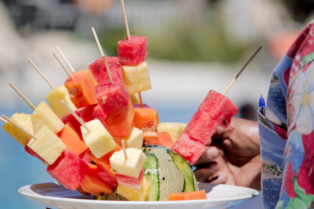 a white plate topped with watermelon and pineapple skewers