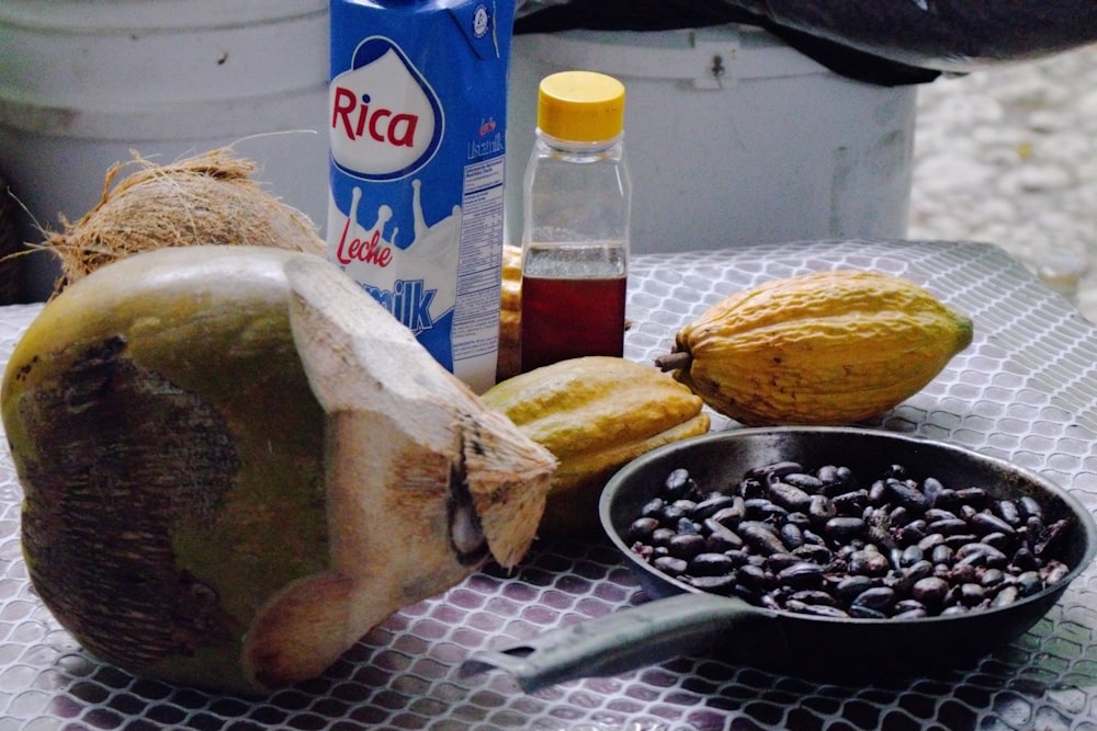 a table topped with a bowl of fruit and a bottle of liquid