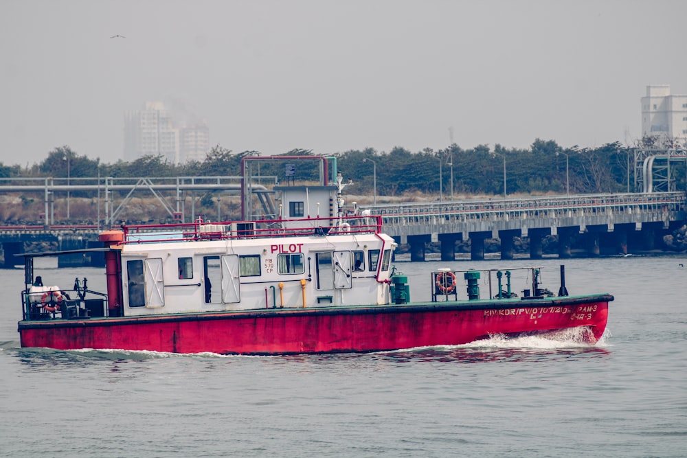 a red and white boat traveling down a river