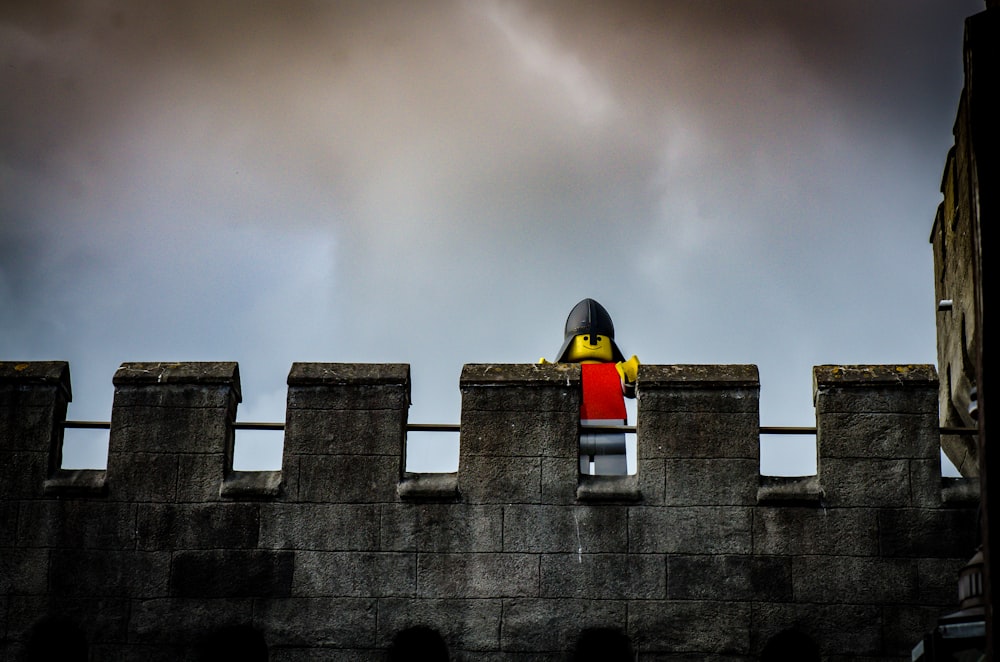 a lego man standing on top of a stone wall