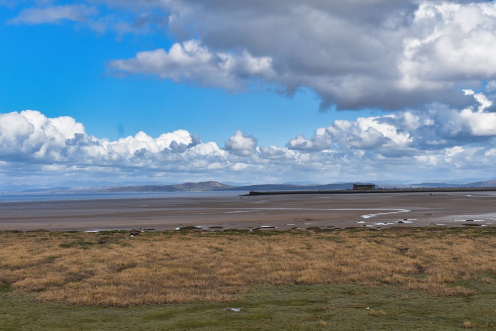 a grassy field with a body of water in the distance