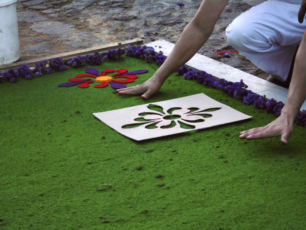 a person kneeling down on a patch of green grass