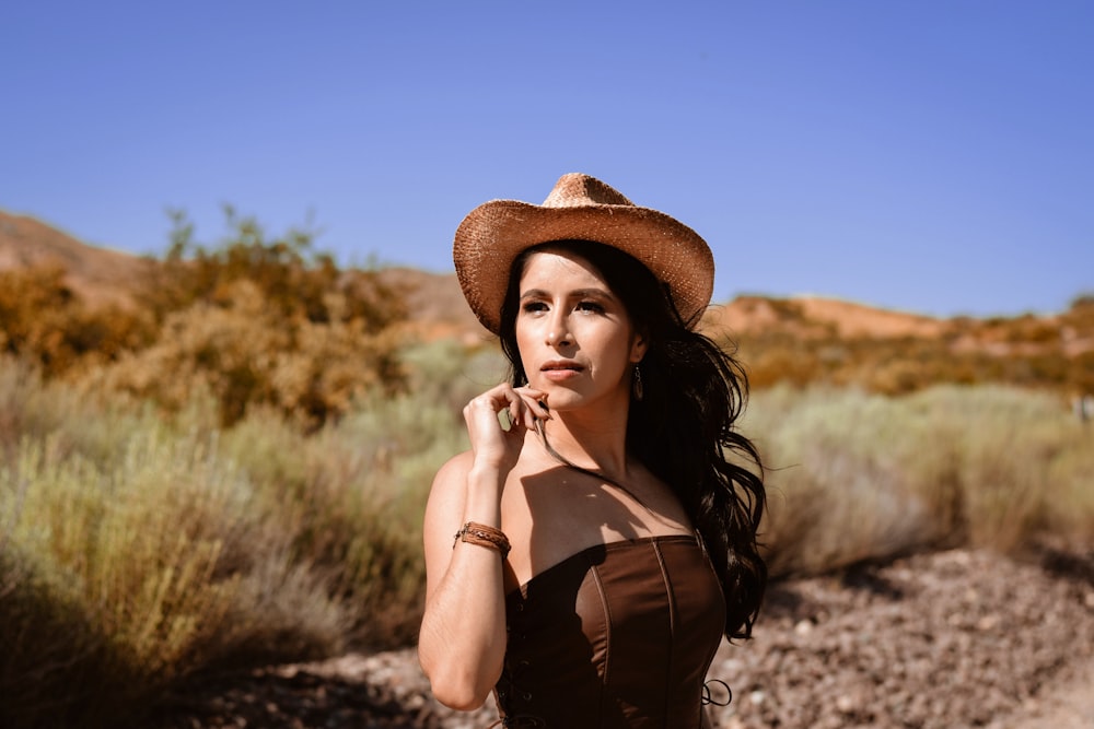 a woman wearing a brown dress and a cowboy hat