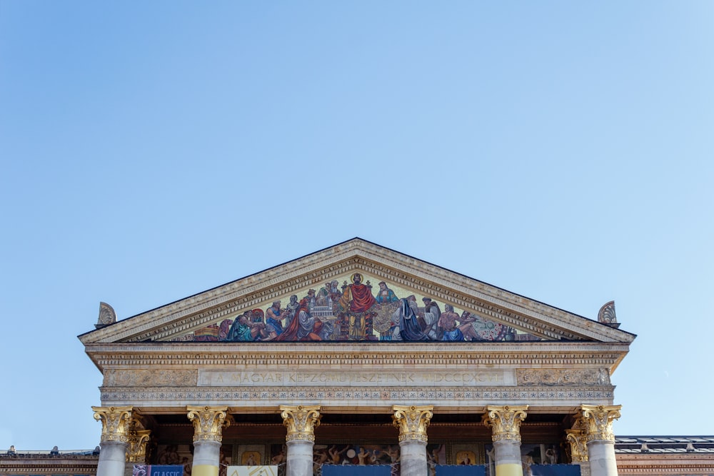 a large building with columns and paintings on it