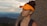 a woman wearing an orange visor on top of a mountain