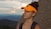 a woman wearing an orange visor on top of a mountain