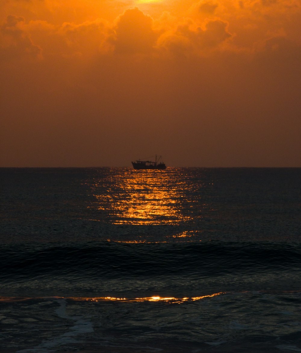 a boat is out on the ocean at sunset