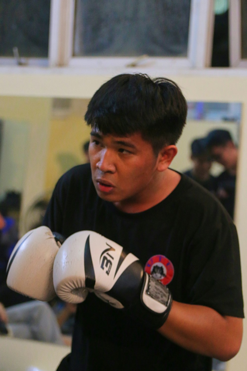 a young man wearing a black shirt and white boxing gloves