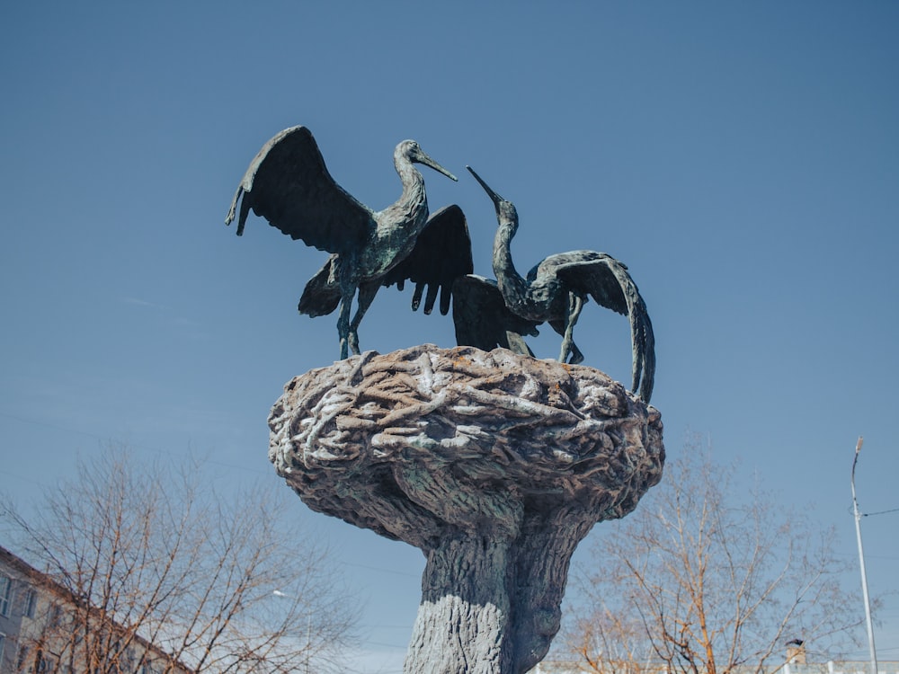 a statue of two birds sitting on top of a tree stump